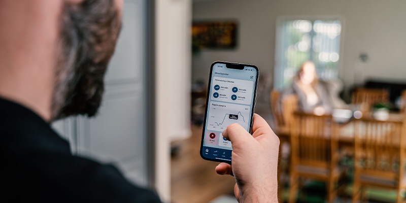 En man följer sin elförbrukning i en app i mobilen. Elförbrukning mäts i kilowattimmar.